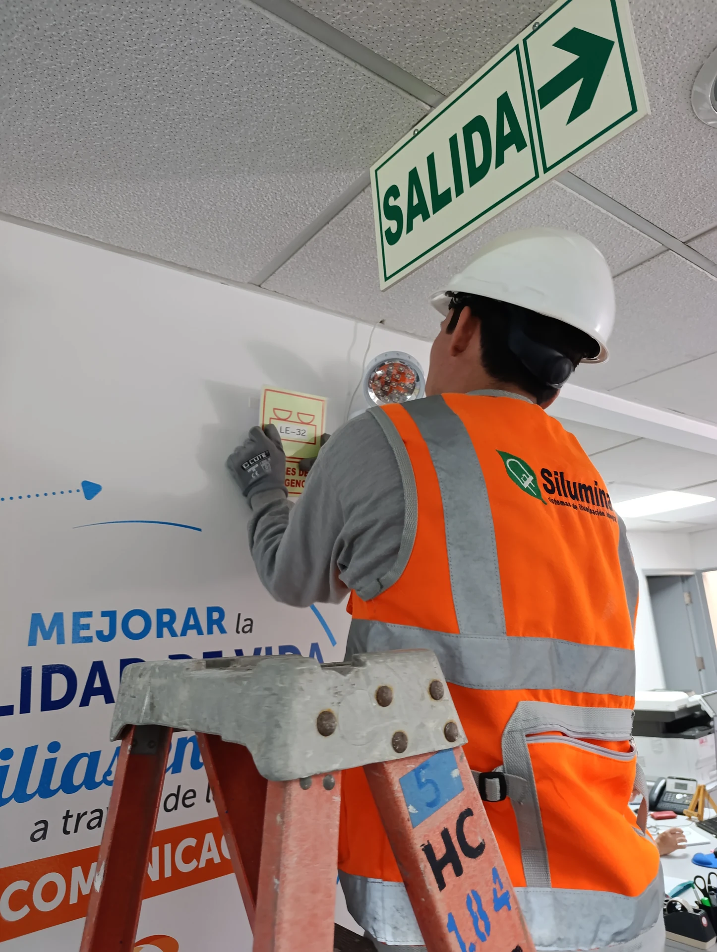 Instalación de señalética SALIDA por técnico en escalera